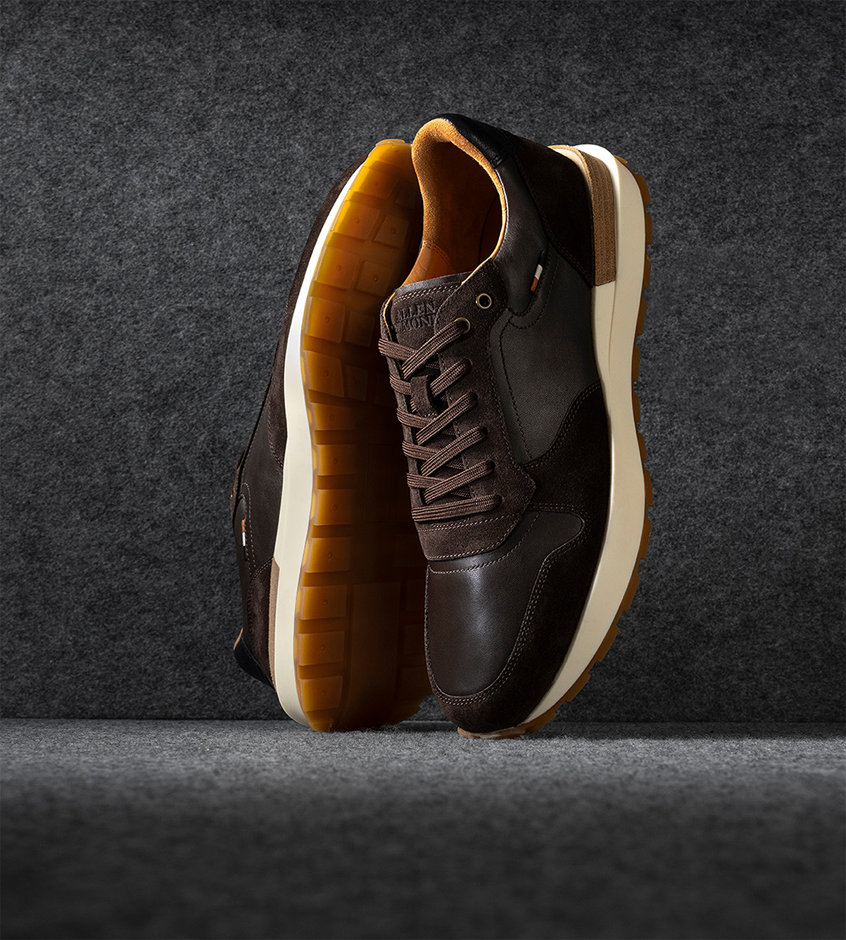 A pair of men’s brown leather sneakers displayed vertically with one sole facing forward.  Une paire de baskets en cuir marron pour hommes affichées verticalement avec une semelle tournée vers l'avant.